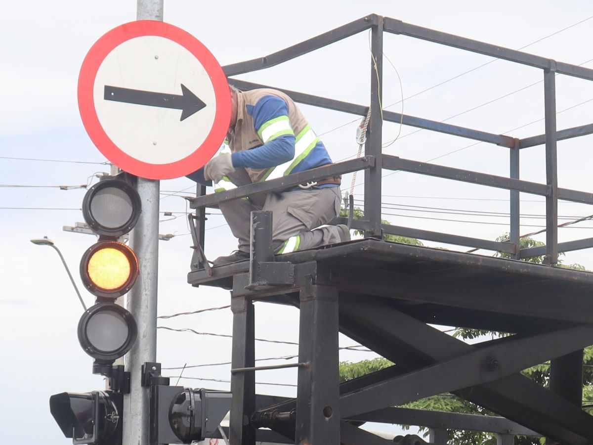 Implantação de placa de sentido da via em coluna semafórica.